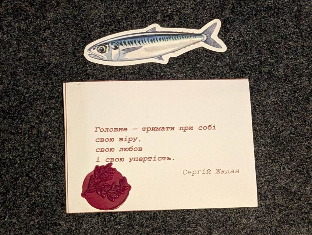 Флаєр вечора і наліпка зі скумбрією. Чотири рядки Сергія Жадана на звороті.