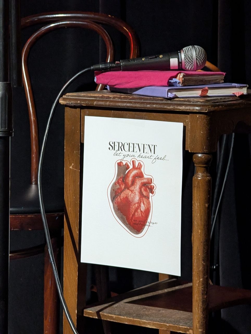 Мікрофон і зошити, з яких читали. На стільчику картка SerceEvent: let your heart feel.